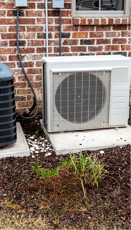 Outdoor air conditioning units beside brick wall.
